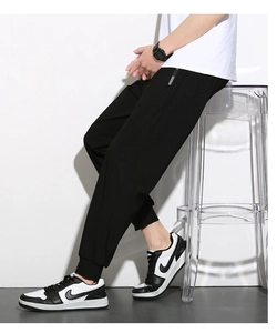 Macro view of men's black ice silk sports pants with silver stripes and ribbed cuffs