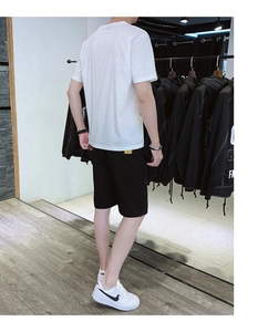 Detail of yellow accent tags on white ice silk t-shirt and black casual summer shorts