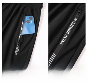Detail of black sports pants featuring a secure zipper pocket with white stripes and logo