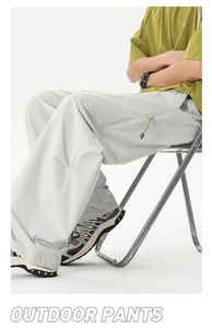 Détail du pantalon cargo gris clair avec poches latérales et fermetures éclair vert néon