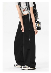Detail of black wide-leg cargo pants with large side zipper pockets for outdoor wear