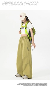 Detail of olive green outdoor cargo pants featuring large zipper side pockets and drawstrings