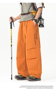 Détail du pantalon cargo orange avec poches zippées et tissu coupe-vent et séchage rapide