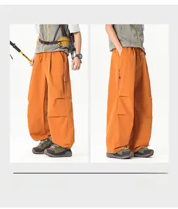 Détail du pantalon cargo orange à jambes larges avec plis aux genoux et poches zippées