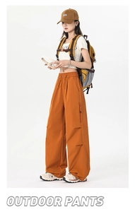 Detail of orange outdoor cargo pants with elastic drawstring waist and side zipper pocket