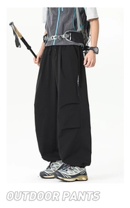 Détail du pantalon cargo noir avec poches zippées cachées et texture de tissu coupe-vent