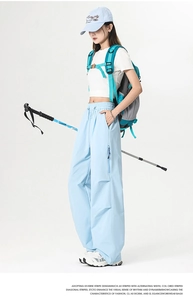 Detail of light blue wide-leg cargo pants with zipper pockets for outdoor activities