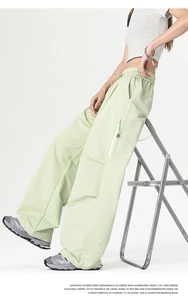 Detail of light green cargo pants featuring elastic drawstring waist and side zipper pocket
