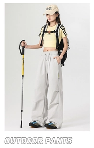 Detail of light grey outdoor pants featuring an elastic drawstring waist and side zip pockets