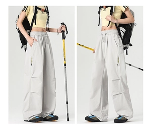 Detail view of light grey outdoor pants with vertical zipper pockets and elastic drawstring