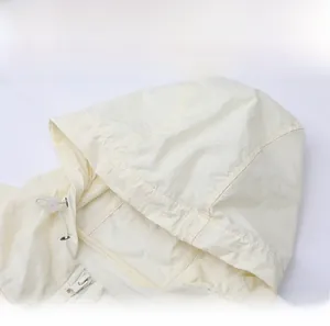 Detail view of the beige hooded sun protection jacket with adjustable drawstring and zipper
