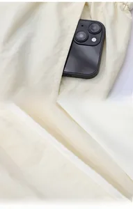 Detail of diagonal side pocket on beige sun protection shorts showing phone storage depth