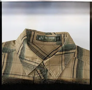 Close-up of khaki plaid cotton shirt collar with brand label and metal buttons
