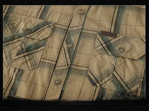 Macro shot of khaki plaid cotton shirt featuring double breast pockets and metal buttons