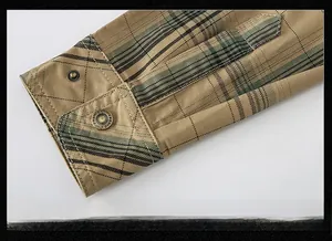 Detail view of the khaki plaid shirt cuff featuring a vintage metal button with engraving