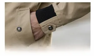 Detailed close-up of khaki jacket featuring metal snap pocket and ribbed knitted cuff