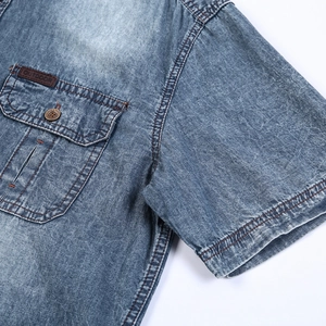 Detail of light blue denim shirt showing outdoor leather patch and metal buttons