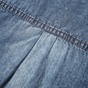 Macro view of blue denim shirt fabric showing texture, double yellow stitching, and back pleat