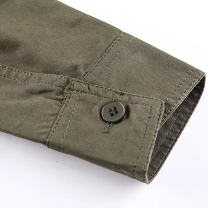 Close-up of olive green cotton twill shirt cuff with a dark brown four-hole button