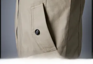 Detail of light khaki jacket featuring a slanted pocket with a black decorative button