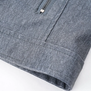 Detailed close-up of heavy-duty metal zipper and gray-blue denim texture on a jacket