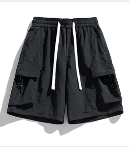 Detail of black cargo shorts featuring elastic waistband, white drawstrings, and utility pockets