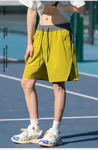 Detail of yellow athletic shorts with grey ribbed waistband and reflective side stripes