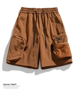 Macro detail of men's functional cargo shorts with orange mesh pocket and drawstring