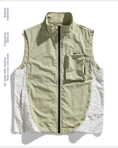 Dettaglio ravvicinato di un gilet sportivo verde salvia con inserti bianchi e multitasche