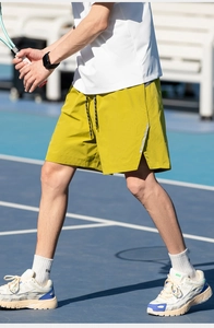 Detail of mustard yellow sports shorts featuring reflective side stripes and drawstring