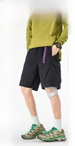 Detail of black cargo shorts featuring purple adjustable waist strap and large side pockets