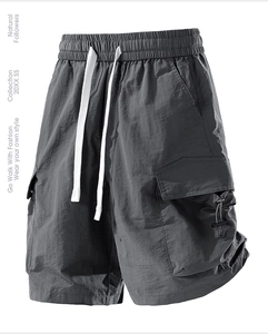 Detail view of dark grey cargo shorts with elastic waist, drawstring, and side utility pockets