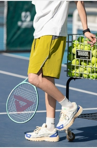Detail of green sports shorts with gray contrast stripes and side slits on tennis court