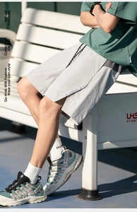 Detail of light gray sporty shorts with side split hem and contrast drawstring waist