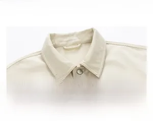 Close-up of beige corduroy jacket featuring a sharp lapel and metallic button detail