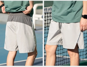 Detail view of men's athletic shorts showing split hem and gray patchwork fabric
