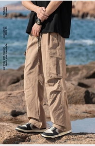 Close-up of khaki cargo pants with drawstring waist and large flap pockets by the sea