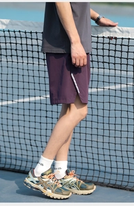 Detail of magenta sports shorts featuring white side stripes on a tennis court