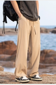 Outdoor view of khaki hiking pants featuring an adjustable drawstring and a relaxed straight fit