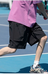 Male athlete in motion wearing quick-dry cargo shorts with zipper pockets on a blue court