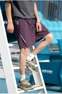 Detail of purple quick-dry athletic shorts featuring reflective stripes and drawstring waist