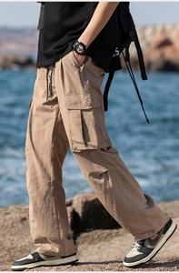 Detail of khaki outdoor cargo pants featuring large side pockets and drawstrings on rocks