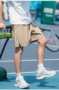 Detail of khaki cargo shorts featuring reflective silver side stripes on a tennis court