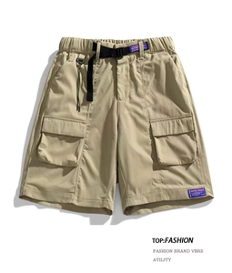 Detail of khaki cargo shorts showing elastic waist with black buckle belt and flap pockets