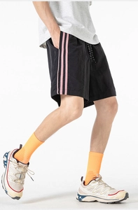 Dettaglio ravvicinato di pantaloncini sportivi neri traspiranti con strisce laterali rosa