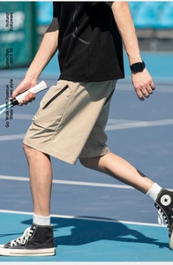 Detail of khaki cargo shorts featuring a functional black zipper pocket and smooth texture
