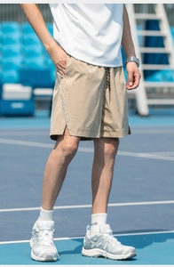 Detail of light khaki quick-dry sports shorts with reflective side strips on tennis court