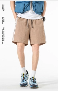 Dettaglio dei pantaloncini sportivi kaki con vita elastica a coulisse e strisce laterali