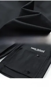 Detail of black water-repellent cargo shorts with large pocket and white embroidery