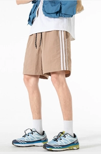 Dettaglio di pantaloncini sportivi kaki con strisce laterali e gilet tattico